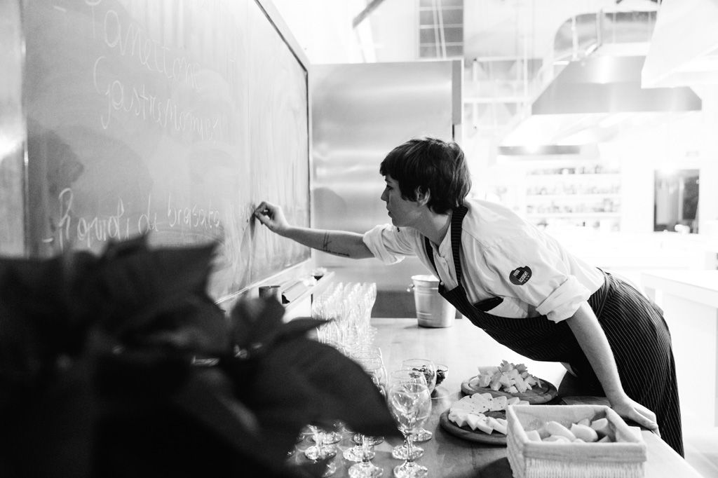 Fotografo Eventi Esclusivi Gilead FoodGeniusAcademy Una cuoca scrive sulla lavagna il menu della giornata in uno scatto di Della Savia, fotografo di feste e cene aziendali