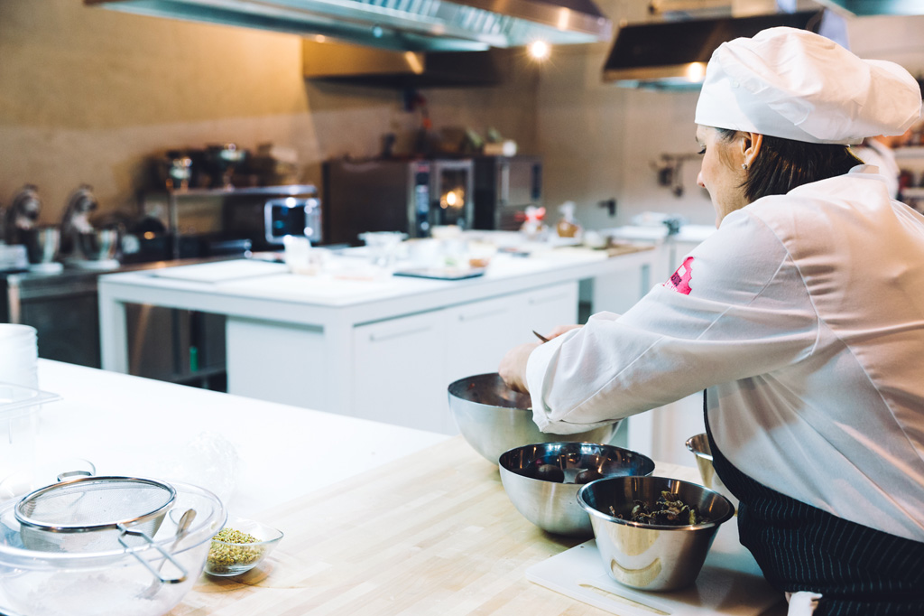 Fotografo Eventi Esclusivi Gilead FoodGeniusAcademy Una cuoca taglia il cioccolato in cucina