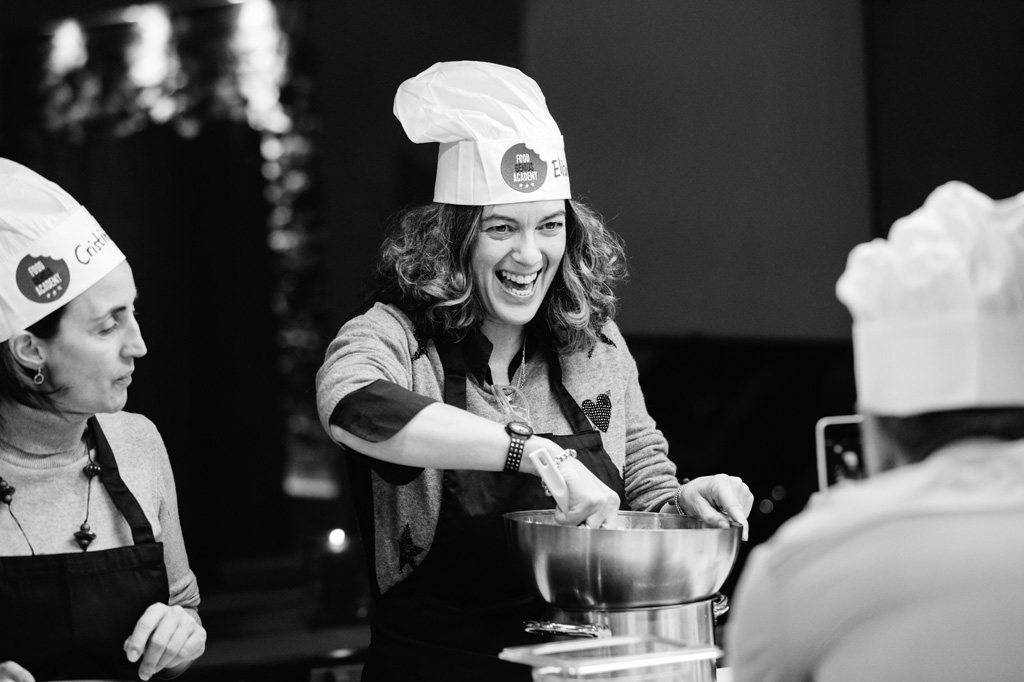 Fotografo Eventi Esclusivi Gilead FoodGeniusAcademy Un'invitata mescola gli ingredienti da cucinare
