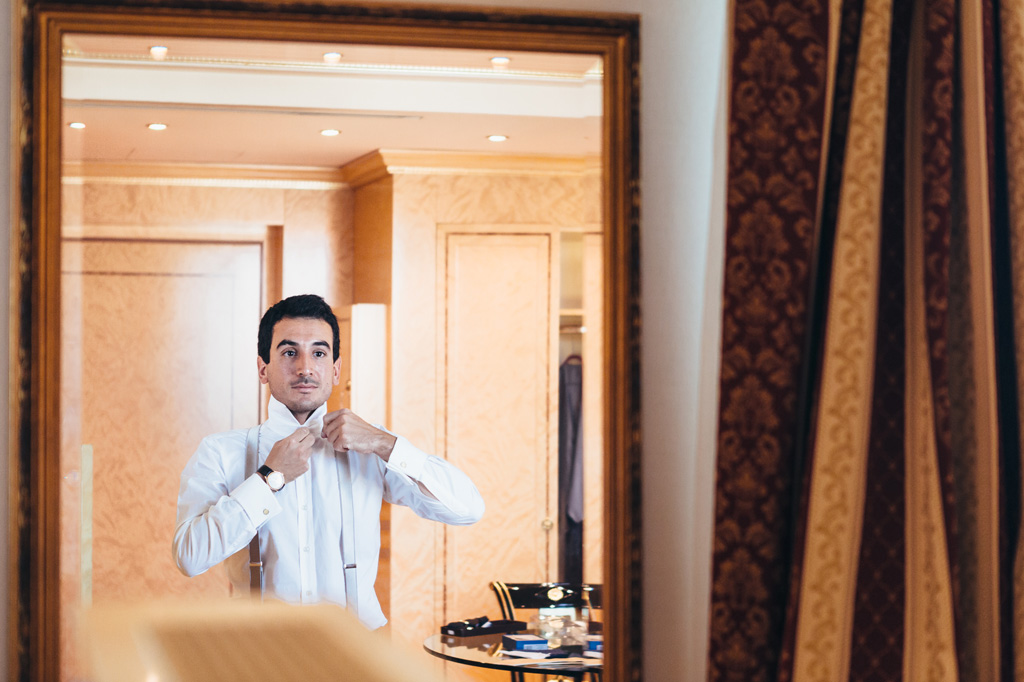 Fotografo Matrimonio Villa Caroli Zanchi Lo sposo indossa una camicia bianca davanti allo specchio