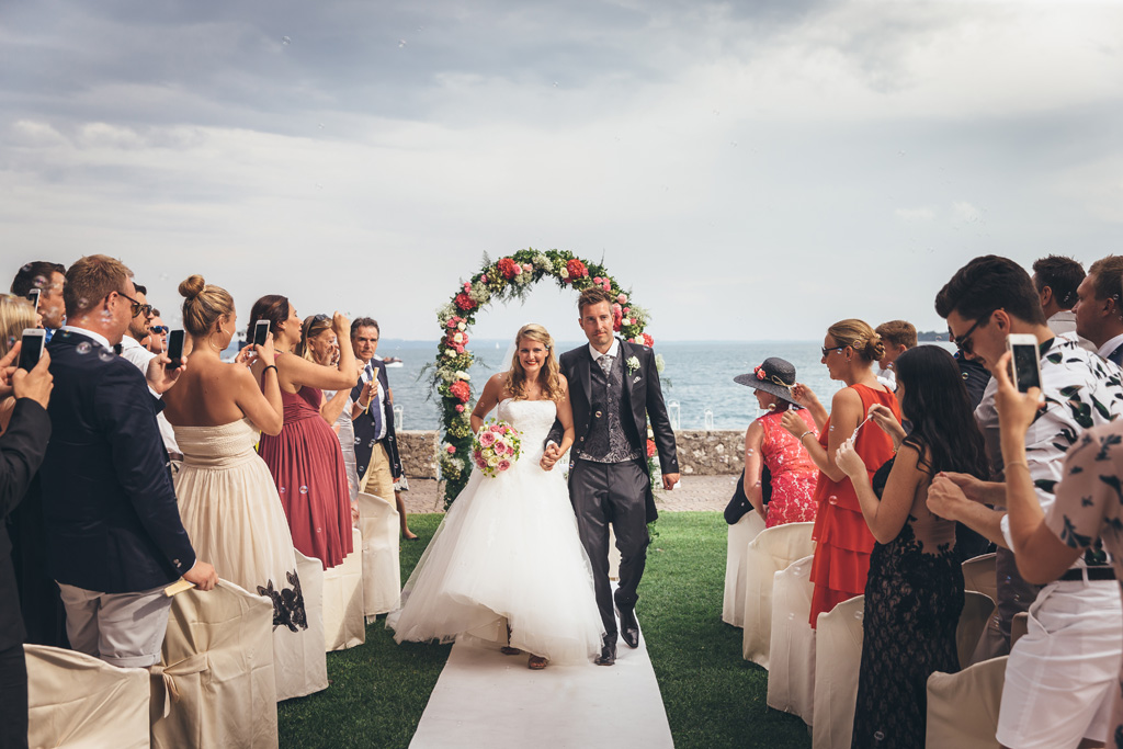 Fotografo Matrimonio Lago di Garda I due sposi attraversano telo bianco a seguito della cerimonia di matrimonio