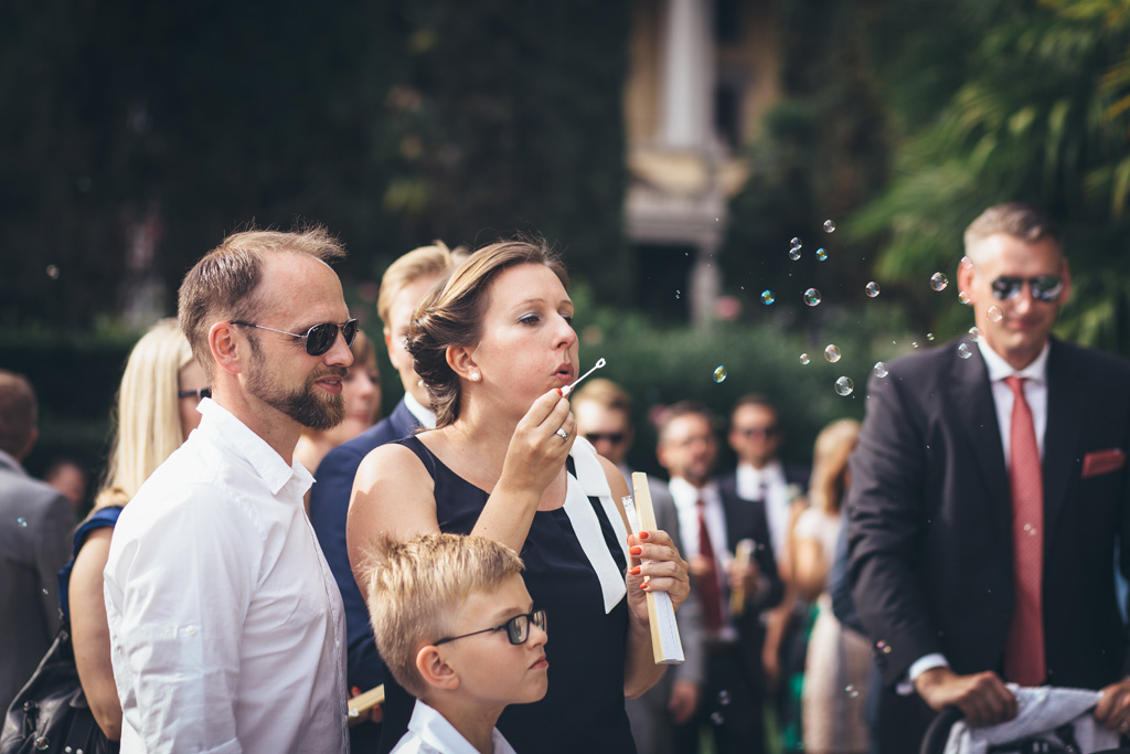 Fotografo Matrimonio Lago di Garda Un'invitata soffia le bolle di sapone in direzione degli sposi