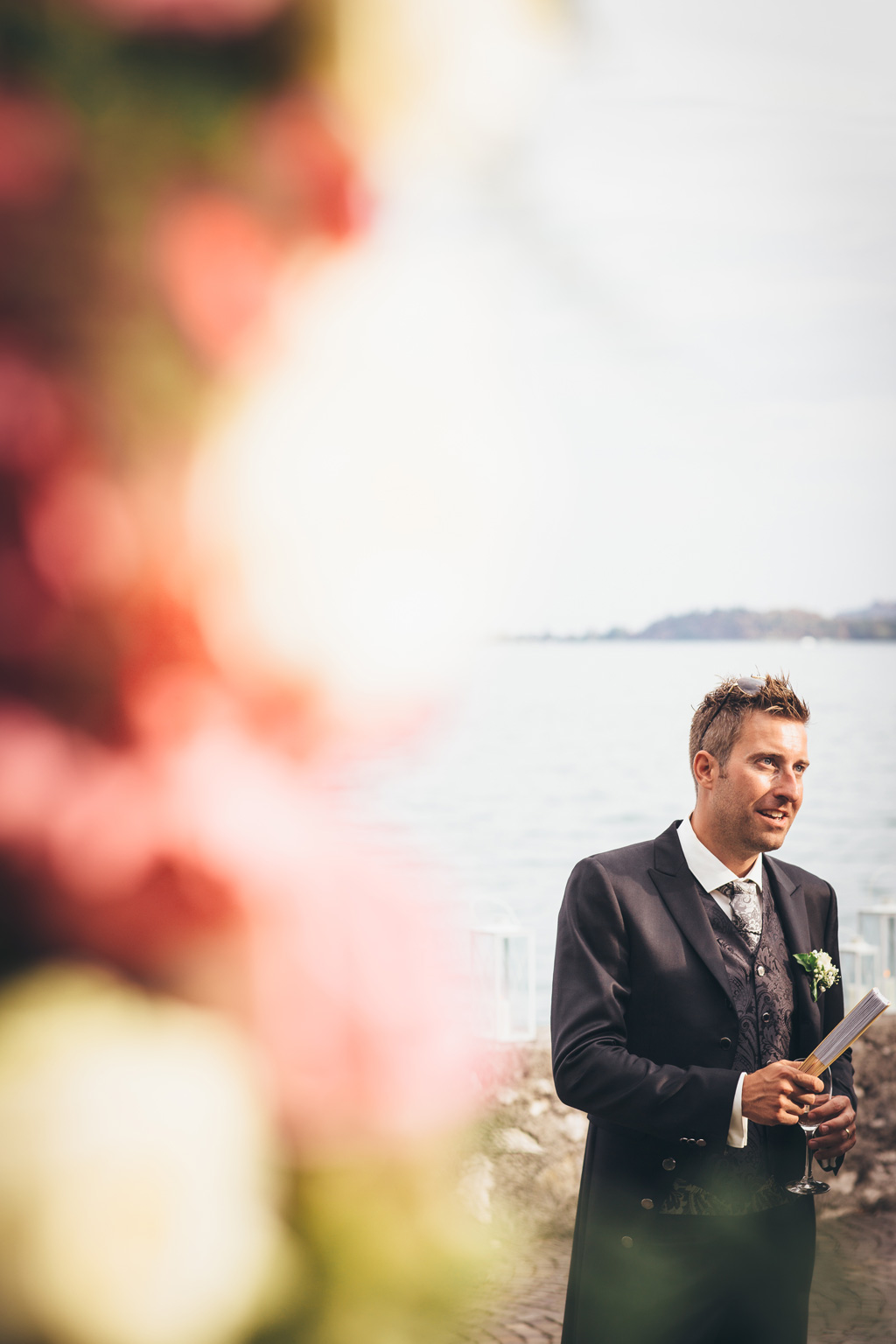 Fotografo Matrimonio Lago di Garda Lo sposo tiene un bicchiere e un ventaglio in mano