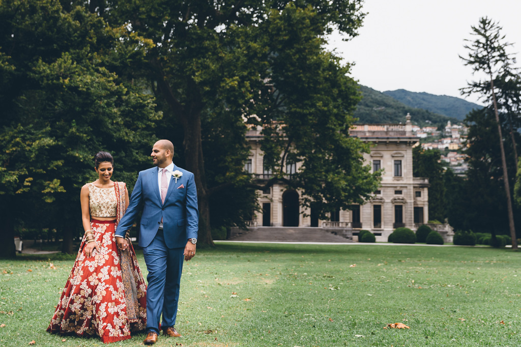 Fotografo Matrimonio Villa Erba I due sposi passeggiano lungo il prato verde