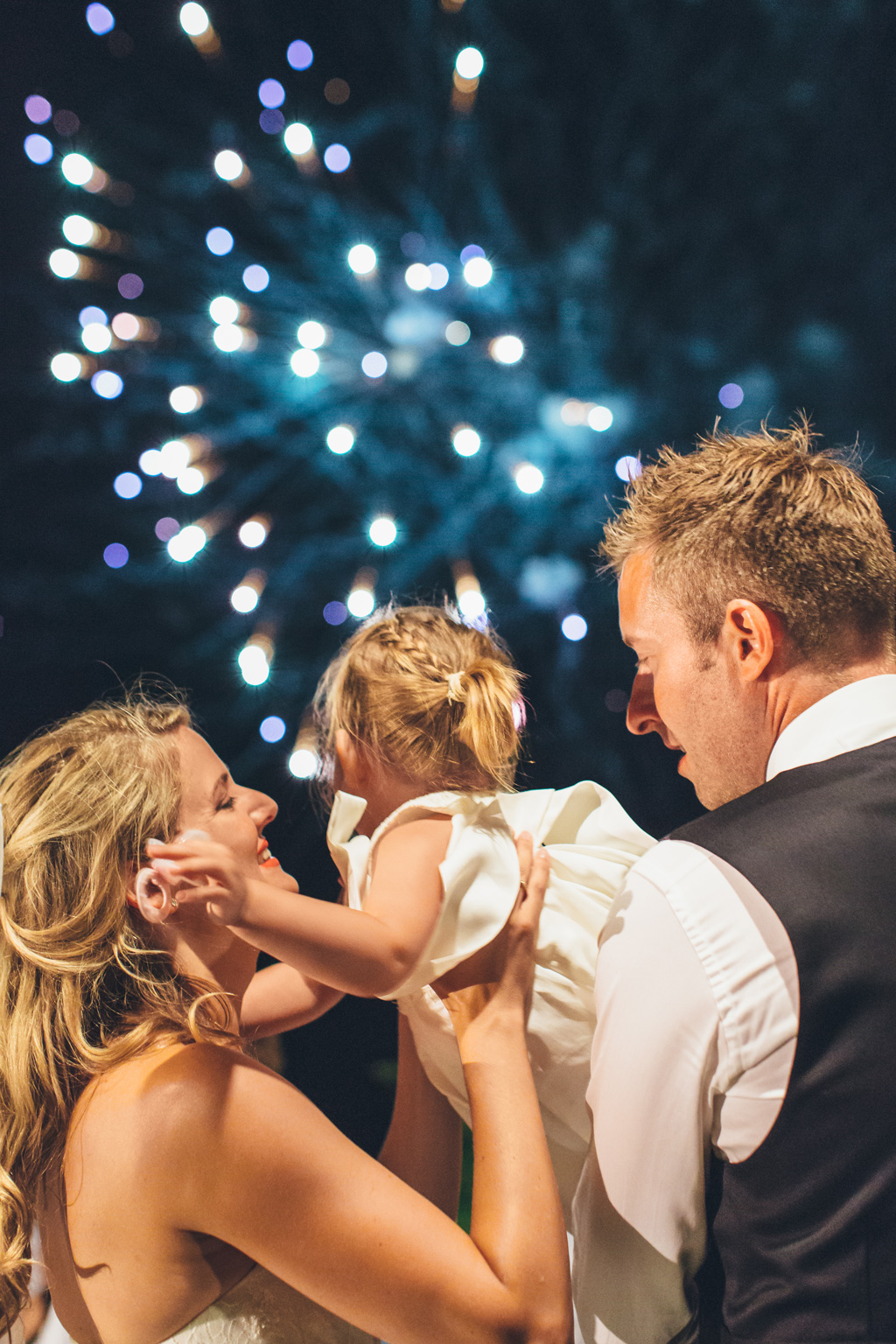Fotografo Matrimonio Lago di Garda Gli sposi stringono una bambina durante i botti d'artificio
