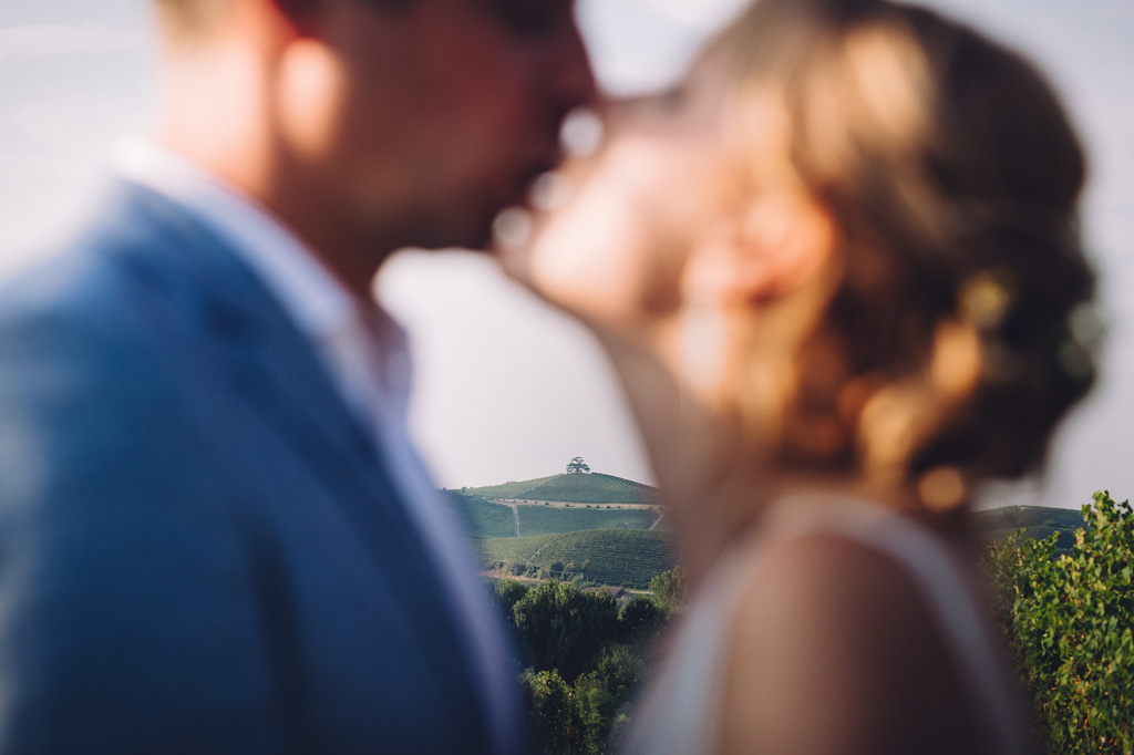 Fotografo Matrimonio Langhe I due sposi si scambiano un bacio romantico nell'ambiente bucolico delle Langhe