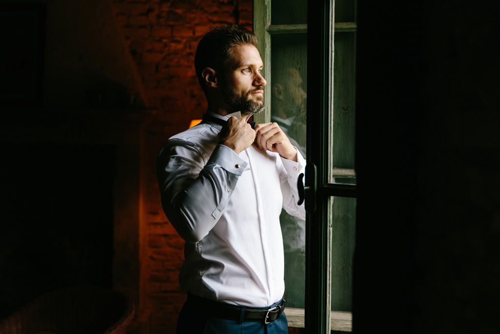 Fotografo Matrimonio Convento Dell'Annunciata Medole Lo sposo si sistema la camicia davanti alla finestra della sua camera