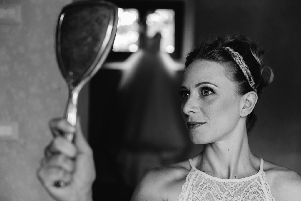 Fotografo Matrimonio Convento Dell'Annunciata Medole Laura si guarda allo specchio per vedere il risultato finale del trucco