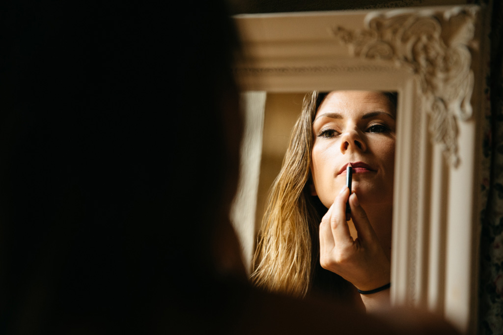 Fotografo Matrimonio Basilica San Galgano Toscana La sposa si trucca le labbra allo specchio della sua camera d'albergo