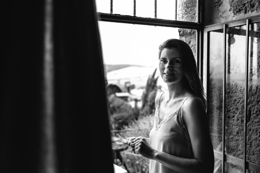 Fotografo Matrimonio Basilica San Galgano Toscana Ritratto della sposa alla finestra della sua camera d'albergo