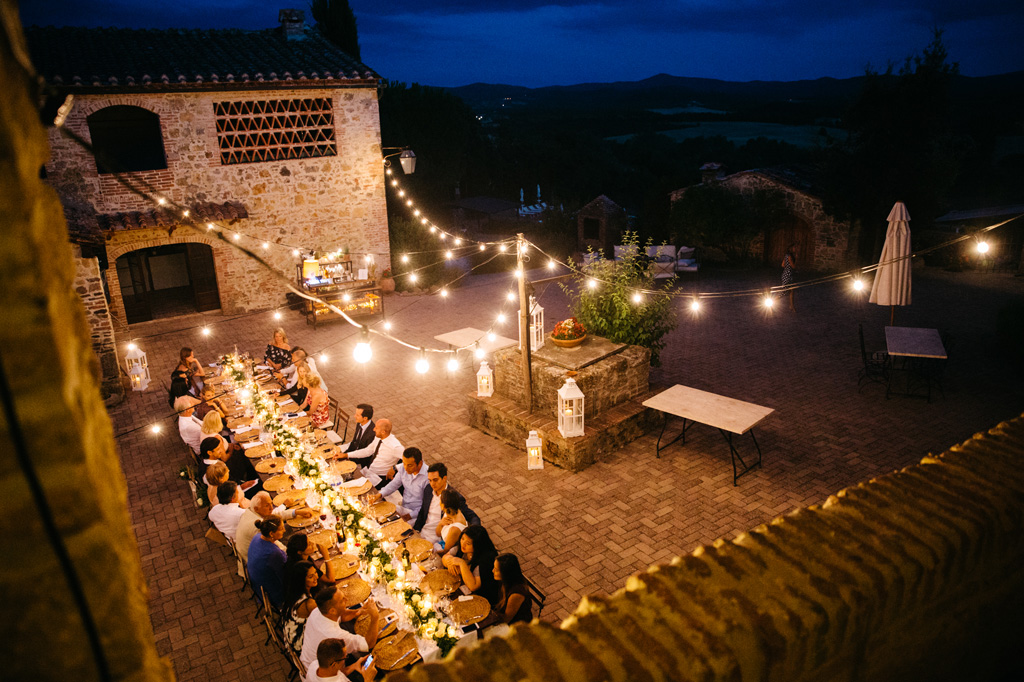 Fotografo Matrimonio Basilica San Galgano Toscana Il tavolo illuminato da tante lampadine al ricevimento di Carlos e Catherine