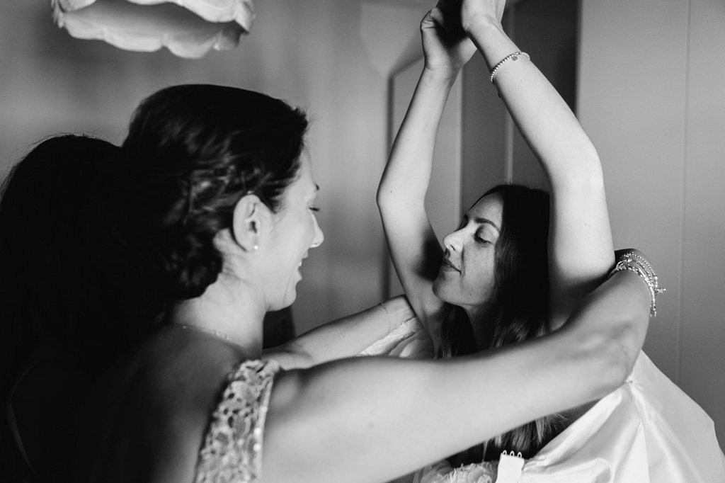 Wedding Photographer Como Lake L'amica aiuta la sposa a indossare l'abito