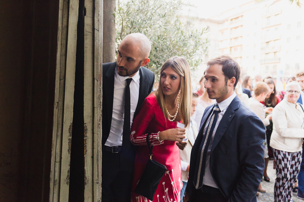 Wedding Photographer Como Lake Alcuni invitati sbirciano dentro la chiesa aspettando l'uscita degli sposi