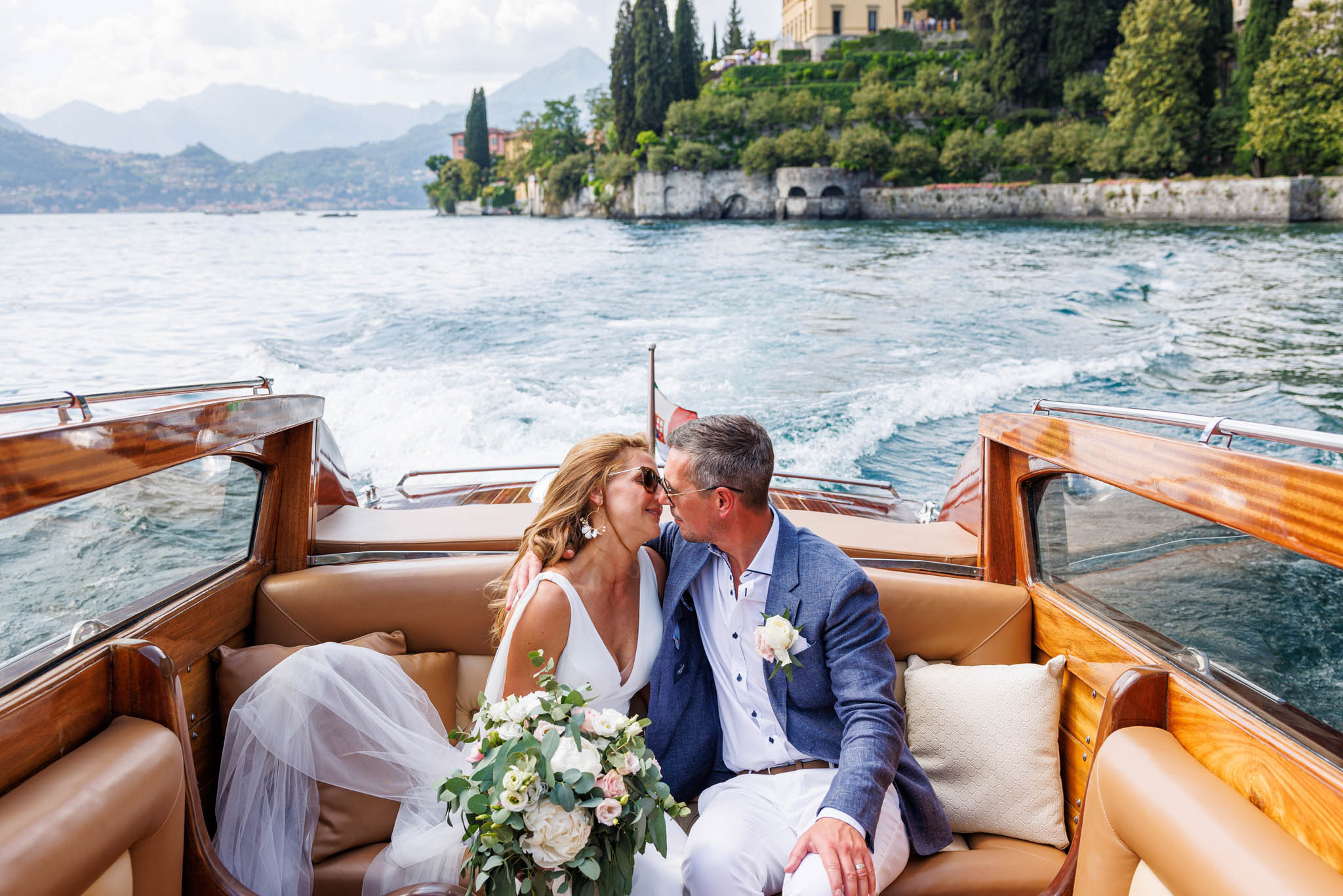 Destination Wedding Photographer Como Lake Gli sposi che si baciano in barca sul lago di como al loro matrimonio