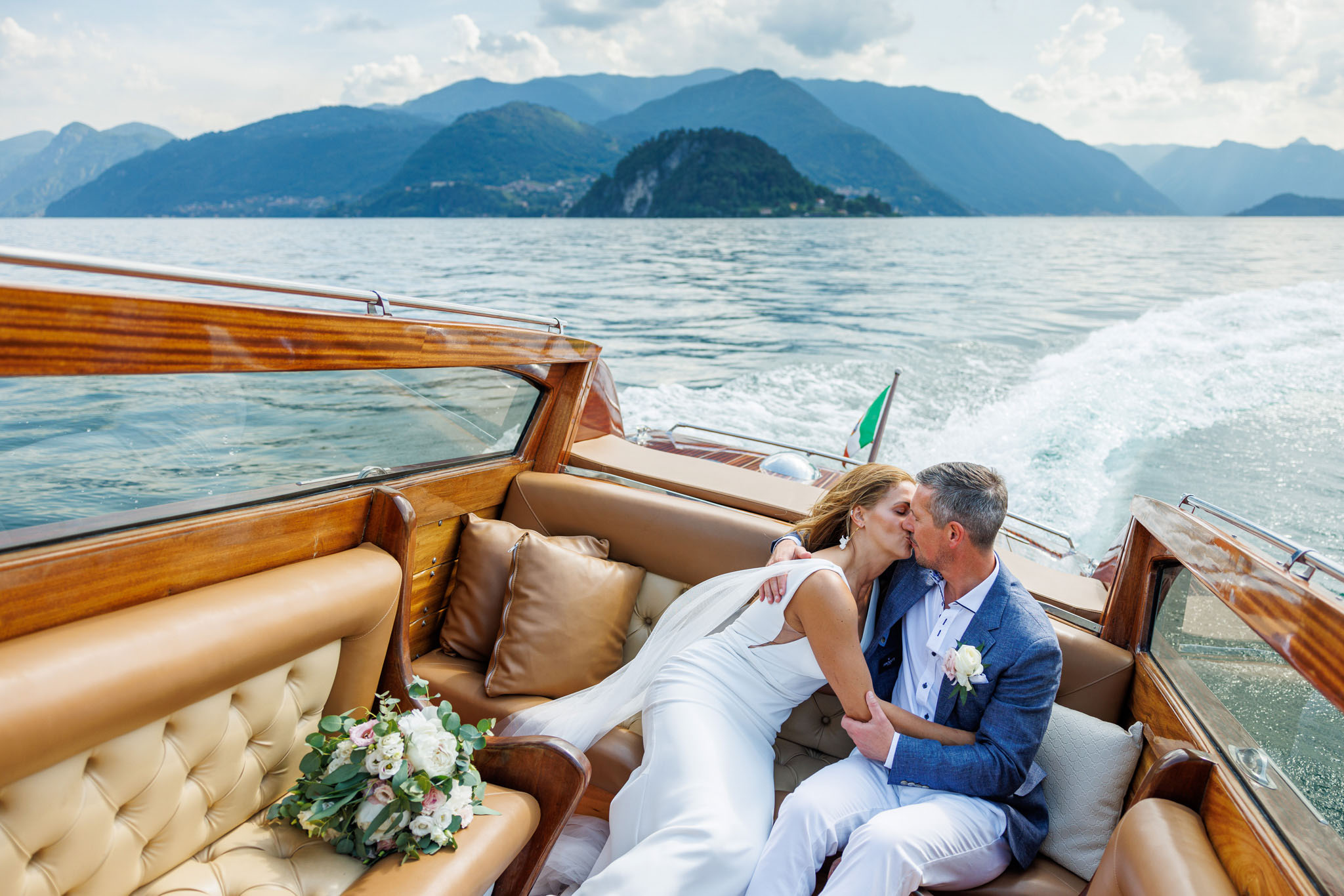 Destination Wedding Photographer Como Lake Gli sposi che si baciano in barca sul lago di como al loro matrimonio